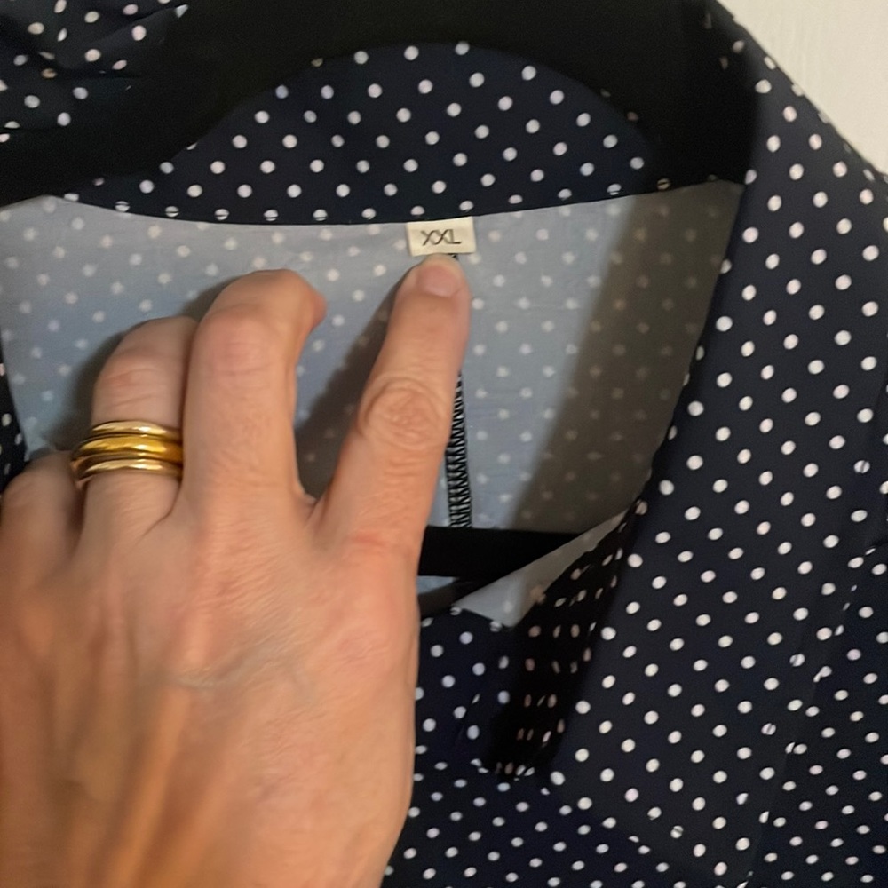 Long sleeve button down navy top with white polka dots. Two pockets at chest.